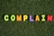 Capital letter `Complain` word from colorful of wood on grass background.