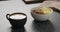 Cappuccino in black cup with granola with mango in white bowl on kitchen