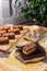 Cappuccino and Chocolate brownie with nuts on a black plate on a yellow set on a wooden table in a restaurant