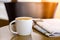 Cappuccino coffee cup on wooden table with newspaper