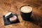 Cappuccino coffee with latte art on wooden table. Black cup, beautiful milk foam and macaroon cookies. Soft focus