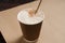 Cappuccino coffee with vanilla crumbs in a brown disposable paper cup with a straw