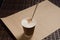 Cappuccino coffee with vanilla crumbs in a brown disposable paper cup with a straw