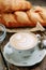 Cappuccino coffee on a wooden table with a loaf of bread. Breakfast with a buttered bun and a Cup of coffee