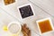 Cappuccino cup, three white ceramic bowl of fruit jams and cinnamon sticks on the wooden background.