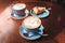cappuccino cups with cheese cake on the brown wooden table in cafe, modern breakfast and resting time concept in restaurant