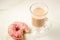 Cappuccino glass with bitten donut/cappuccino glass with bitten donut on a white marble background. Top view