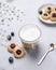 Cappuccino or latte with milk foam in a cup with handmade berry cookies and blueberries on a light background with gypsophila