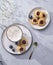 Cappuccino or latte with milk foam in a cup with handmade berry cookies and blueberries on a light background with gypsophila