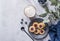 Cappuccino or latte with milk foam in a cup with homemade berry cookies in a dark plate and blueberries on a light background