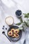 Cappuccino or latte with milk foam in a cup with homemade berry cookies in a dark plate and blueberries on a light background