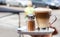 a cappuchino on a glass and cinnamon shaker, outdoors.