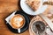 Cappucino, apple tart, poaceae and a basket of seasoning on a wood background