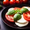 Caprese salad on a black plate. Tomatoes, mozzarella cheese and basil