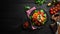 Caprese salad on a black plate. Tomatoes, mozzarella cheese and basil. Top view.