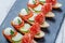 Caprese sandwiches with tomato, mozzarella cheese, basil, salami on ciabatta bread on stone slate background close up.