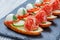 Caprese sandwiches with tomato, mozzarella cheese, basil, salami on ciabatta bread on stone slate background close up.