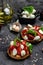 Caprese toasts with mozzarella, cherry tomatoes and fresh garden basil. Traditional italian appetizer or snack, antipasto.