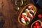 Caprese traditional italian salad in olive wooden bowl on old rustic background.