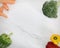 Capsicums, carrots, and broccoli on white marble background.