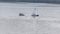 A capsized small sailboat next to an upright sailboat