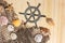 Captains Wheel With Fishing Net and Sea Shells on Wooden Background