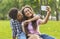 Capturing happy moments. Two cheerful teenagers making selfie outdoors