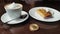 Capuccino, pancake with sour cream and bitcoin gold coin on the table in cafe panorama left to right.