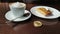 Capuccino, pancake with sour cream and bitcoin gold coin on the table in cafe panorama left to right.