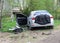 Car accident. A broken gray car on the side of the road with an open door. Road accident and wreckage on the ground and on the