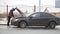 A car accident. A young man opens the hood of a broken car.