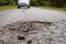 Car approaching huge potholes in asphalt road