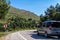 Car on asphalt island road, about to  cornering. Road lined with trees and mountains around