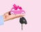 Car with bow and key on dealers palm isolated on a pink background.