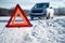 Car breakdown on a road in winter. Winter driving. Warning triangle on the road, waiting for help.