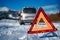 Car breakdown on a road in winter. Winter driving. Warning triangle on the road, waiting for help.