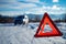 Car breakdown on a road in winter. Winter driving. Warning triangle on the road, waiting for help.