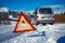 Car breakdown on a road in winter. Winter driving. Warning triangle on the road, waiting for help.