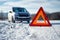 Car breakdown on a road in winter. Winter driving. Warning triangle on the road  waiting for help.