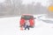 Car breakdown in snowfall in bad weather. Woman sits near an emergency stop sign in snowdrift in winter. Danger of driving in