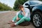 Car breakdown, young man sitting on spare tyre