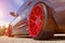 A car with bright red beautiful wheels parked in a parking on a clear sunny day