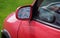 Car with broken side door mirror. Red car in green background. Asociative.