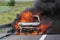 A car burning on a highway with thick black smoke