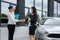 Car buy deal. Two beautiful women handshaking near new car standing outside and smilling