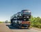Car carrier trailer with cars on bunk platform. Car transport truck on the highway