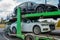 The car carrier transports new cars. A trailer for transporting cars is at a gas station. The concept of road transportation