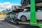 The car carrier transports new cars. A trailer for transporting cars is at a gas station. The concept of road transportation