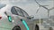 Car charging on the background of a windmills and solar panels. Charging electric car. Electric car charging on wind