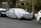 A car cover on an old car in a suburban street in Melbourne